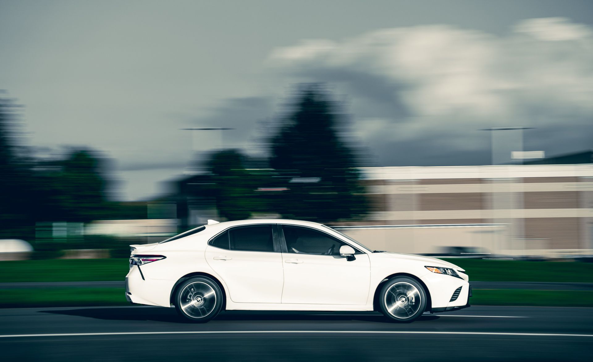 Dynamic shot of a white car speeding on the city road, blurred background creating a sense of motion.